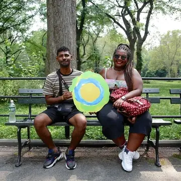 A couple in the park with the Idealist logo between them.