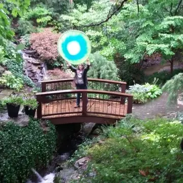 Someone on a bridge holding an Idealist logo over their head.