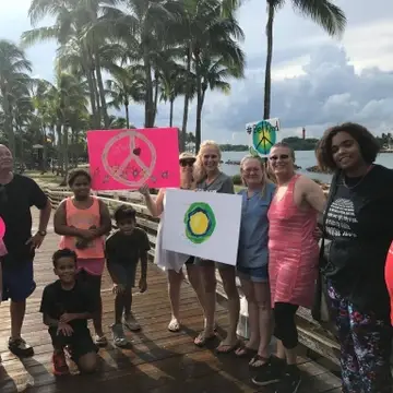 A group of people holding up the Idealist logo and other rally art.