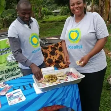 Two people work behind a table wearing Idealist shirts.