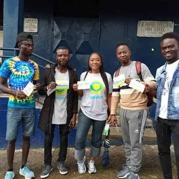 A group of people pose with a card that says Idealist on it.